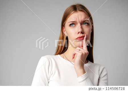 Young Woman Holding Hand to Face on gray background Young Woman Holding Hand to Face on gray background 114506728