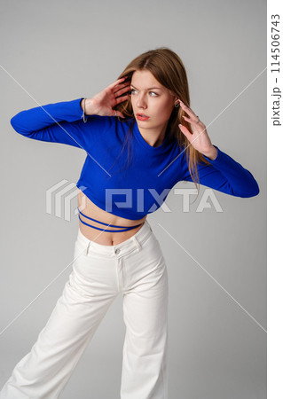 Young Woman model in Blue Top and White Pants posing on white background 114506743