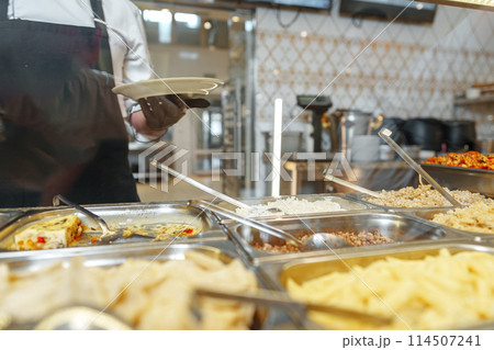 Chef Serving Freshly Cooked Dishes at a Restaurant Buffet During Lunchtime Chef Serving Freshly Cooked Dishes at a Restaurant Buffet During Lunchtime 114507241