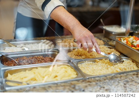 Chef Serving Freshly Cooked Dishes at a Restaurant Buffet During Lunchtime Chef Serving Freshly Cooked Dishes at a Restaurant Buffet During Lunchtime 114507242