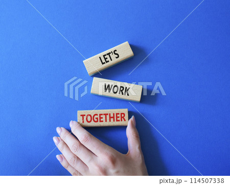 Lets work together symbol. Concept words Less is More on wooden blocks. Businessman hand. Beautiful blue background. Business and Less is More concept. Copy space. Lets work together symbol. Concept words Less is More on wooden blocks. Businessman hand. Beautiful blue background. Business and Less is More concept. Copy space. 114507338