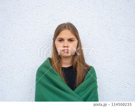 Portrait of a teenage girl looking at the camera. Young sad thinking curious child looks at the camera close-up. Face and eyes Serious contemplative child. 114508233