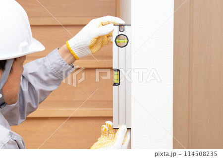 水平器（水準器、レベル）を使って壁の垂直を調べる作業員 114508235