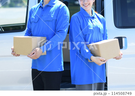 屋外で荷物を運ぶ配送ドライバーの男女 屋外で荷物を運ぶ配送ドライバーの男女 114508749