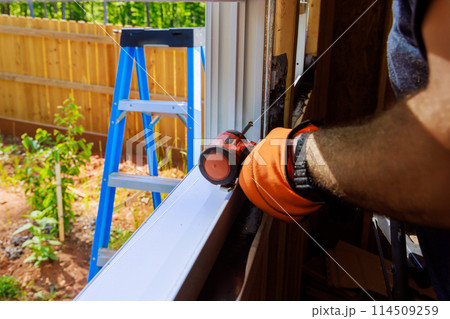 New house construction worker installing plastic windows with screwdriver 114509259