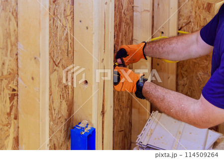 During installation electrical wires on interior of residential construction site, an electrician installs wires 114509264