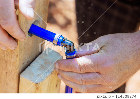An experienced plumber connects blue PVC pipe to water piping system 114509274