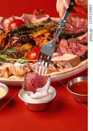 Slice of roast beef on fork dipped into creamy sauce Slice of roast beef on fork dipped into creamy sauce 114510963