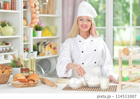 Portrait of beautiful young woman in chefs hat baking at home Portrait of beautiful young woman in chefs hat baking at home 114511007