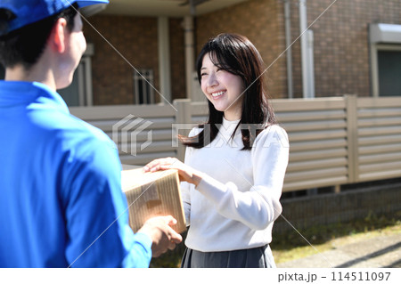 宅配ドライバーから荷物を受け取る若い女性 114511097