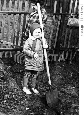 Vintage portrait of a girl with a shovel. A girl with her mother on a cleanup day. Retro. 1970s, USSR. Vintage portrait of a girl with a shovel. A girl with her mother on a cleanup day. Retro. 1970s, USSR. 114512691