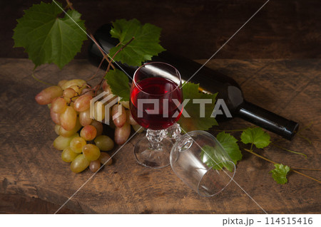Still life with glasses of red wine and grapes on vintage wooden background.. Still life with glasses of red wine and grapes on vintage wooden background.. 114515416