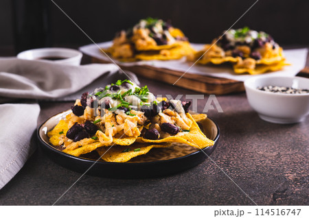 Mexican nacho chips baked with chicken, black beans and cheese on a plate on the table 114516747
