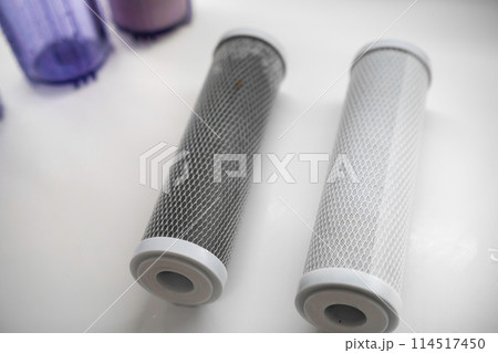 New and used carbon filter for reverse osmosis purification water system on the table in the kitchen. New and used carbon filter for reverse osmosis purification water system on the table in the kitchen. 114517450