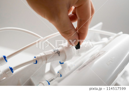 Man hand connect tubes in osmosis water purification filter for home use. Man hand connect tubes in osmosis water purification filter for home use. 114517599