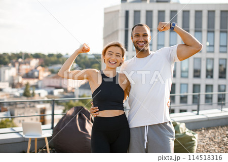 Smiling athletic man and woman showing biceps while exercising healthy lifestyle 114518316
