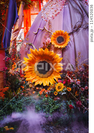Vibrant floral arrangement featuring large artificial sunflowers with lush botanical composition. Magical atmosphere with mist effect, possibly from Las Vegas attraction. 114520836