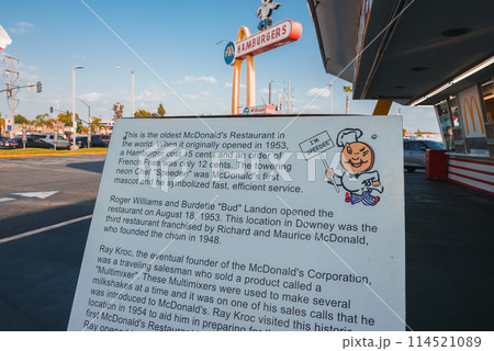 Historical marker at oldest McDonald's in Downey, California. Cartoon chef, iconic restaurant in background with golden arches. Sunny day, LA area landmark. 114521089