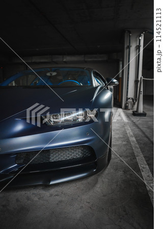 Luxury Bugatti Chiron in metallic blue in underground garage. Sleek design with carbon fiber details, modern LED headlights. Possibly in high end LA location. 114521113