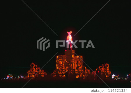 Nighttime desert festival scene with illuminated structure featuring humanoid figure emitting light. Could be reminiscent of Burning Man event in Nevada. 114521324
