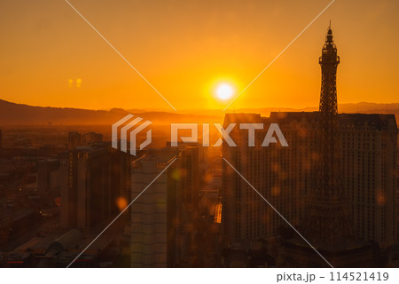 Breathtaking view of Las Vegas Strip at sunset, golden hues light up cityscape with Eiffel Tower hint, serene moment from elevated perspective, skyline in focus. 114521419