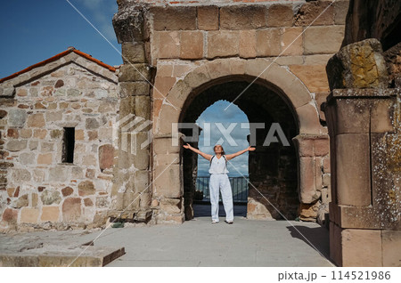 Happy senior traveler woman tourist posing outdoors in ancient Europe fortress ruins. Mature female arms outstretched. Retired old people summer holiday vacation, active lifestyle freedom concept. Happy senior traveler woman tourist posing outdoors in ancient Europe fortress ruins. Mature female arms outstretched. Retired old people summer holiday vacation, active lifestyle freedom concept. 114521986