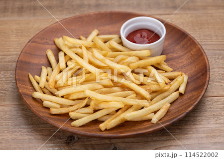 木目のテーブルにフライドポテトとケチャップ 114522002