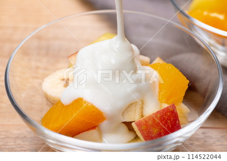 カットしたフルーツにヨーグルトをかける 114522044