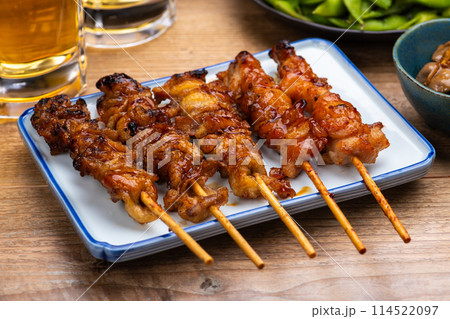 居酒屋のテーブルに並んだ焼き鳥と料理とビール 居酒屋のテーブルに並んだ焼き鳥と料理とビール 114522097