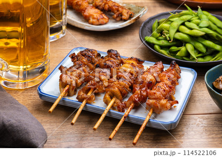 居酒屋のテーブルに並んだ焼き鳥と料理とビール 居酒屋のテーブルに並んだ焼き鳥と料理とビール 114522106
