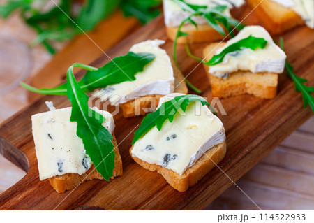Freshly prepared sandwiches with blue cheese and green arugula on wooden board Freshly prepared sandwiches with blue cheese and green arugula on wooden board 114522933