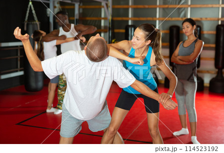 Active girl conducts painful grip on self-defense training in gym Active girl conducts painful grip on self-defense training in gym 114523192