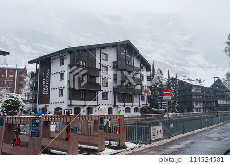 Alpine street view in Zermatt, Switzerland featuring a snowy scene with a building, wooden fence, and no entry sign. Tranquil winter atmosphere captured in this image. 114524581
