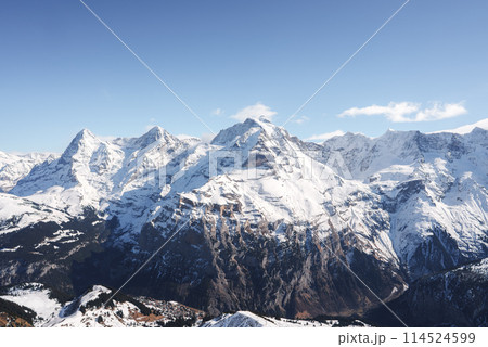 Experience the awe inspiring Swiss Alps with snow covered peaks and rugged slopes captured from the Murren ski resort. Majestic mountains under a clear blue sky create a dramatic alpine scene. Experience the awe inspiring Swiss Alps with snow covered peaks and rugged slopes captured from the Murren ski resort. Majestic mountains under a clear blue sky create a dramatic alpine scene. 114524599
