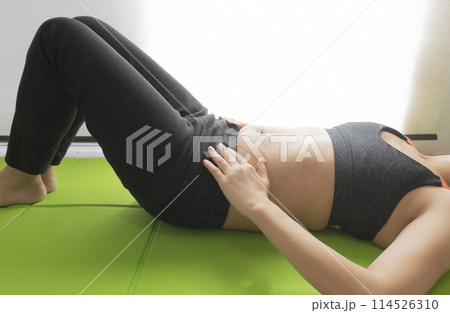 産後の妊娠線が残るお腹とヨガマットの上で仰向けで寝転ぶ女性 産後の妊娠線が残るお腹とヨガマットの上で仰向けで寝転ぶ女性 114526310