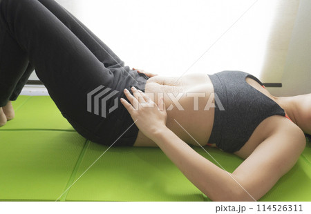 産後の妊娠線が残るお腹とヨガマットの上で仰向けで寝転ぶ女性 産後の妊娠線が残るお腹とヨガマットの上で仰向けで寝転ぶ女性 114526311