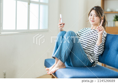 リビングでスマホを操作する若い女性。 114526689