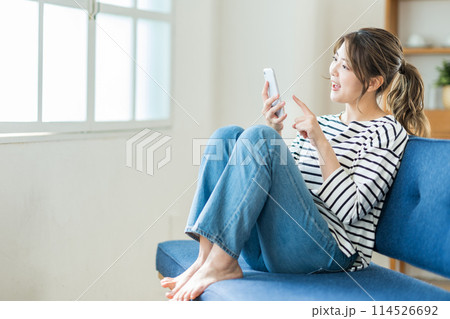 リビングでスマホを操作する若い女性。 リビングでスマホを操作する若い女性。 114526692