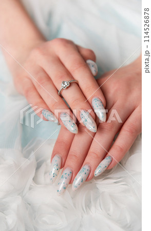 Elegant Hands Featuring Sparkling Ring and Blue Floral Manicure on Delicate White Fabric Elegant Hands Featuring Sparkling Ring and Blue Floral Manicure on Delicate White Fabric 114526878
