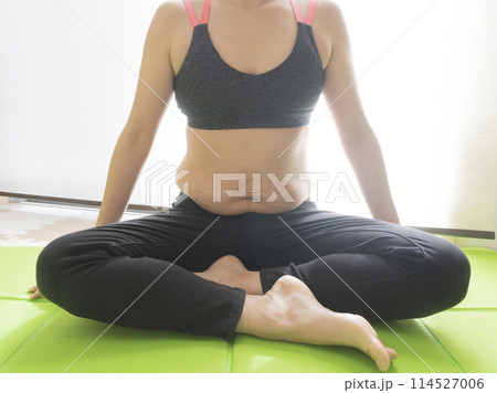 産後の妊娠線が残るお腹とヨガマットの上で胡坐をかく女性 産後の妊娠線が残るお腹とヨガマットの上で胡坐をかく女性 114527006
