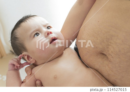 産後の妊娠線が残る女性のお腹と笑顔で抱っこされるハーフの男の子の赤ちゃん 114527015