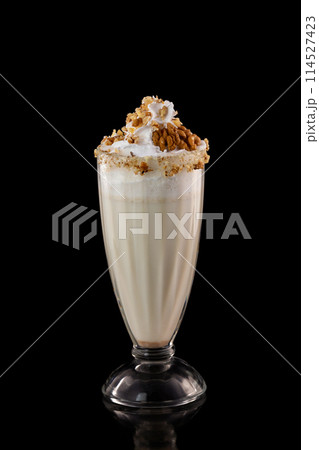 Glass of sweet milkshake with nuts isolated at black background. 114527423