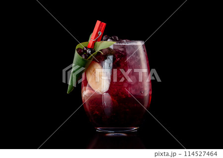 Glass of berries sangria with red wine, black currant, lemon and banana isolated at black background. Glass of berries sangria with red wine, black currant, lemon and banana isolated at black background. 114527464