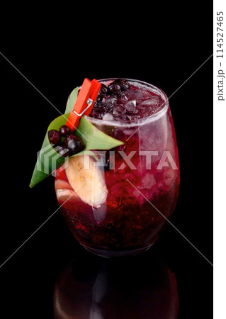 Glass of berries sangria with red wine, black currant, lemon and banana isolated at black background. Glass of berries sangria with red wine, black currant, lemon and banana isolated at black background. 114527465
