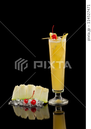 Vertical image of  screwdriver cocktail with orange juice and vodka decorated with cherry and melon isolated at black background. 114527471