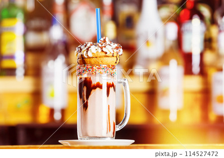 Closeup image of colorful coffee glass decorated with glaze and cookies at bar background. 114527472
