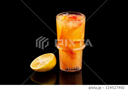 Closeup glass of fresh orange juice with ice isolated at black background. 114527492