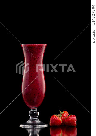 Glass of red currant berries fresh shake decorated with strawberries isolated at black background. Glass of red currant berries fresh shake decorated with strawberries isolated at black background. 114527504
