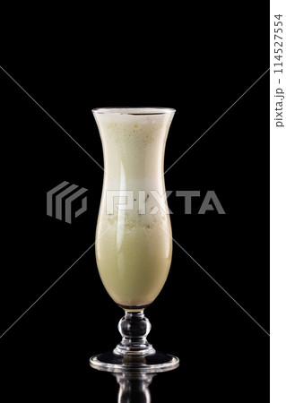 Glass of fresh melon milkshake isolated at black background. Glass of fresh melon milkshake isolated at black background. 114527554
