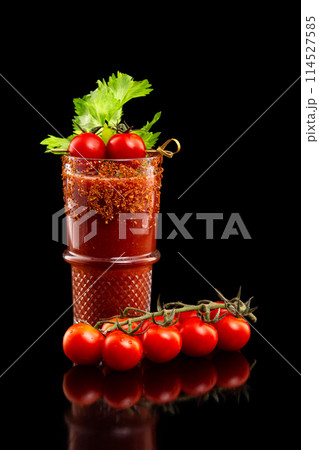 Glass of bloody mary cocktail decorated with celery and pepper and a branch of red tomatoes isolated at black background. 114527585